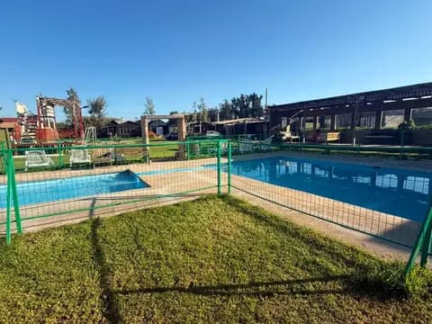 Zona de piscinas familiar con reja de seguridad, césped y área de juegos en Ripamonti Lodge