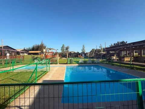 Zona de piscinas protegidas con vista a las cabañas y áreas verdes de Ripamonti Lodge